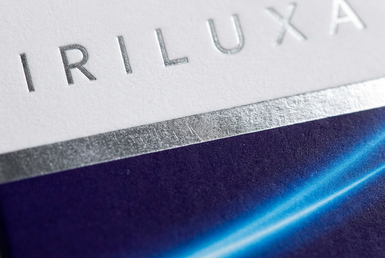 Macro detail of the IRILUXA carton showing its foil and paper finish